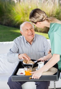 Female Caretaker Serving Breakfast To Senior Man